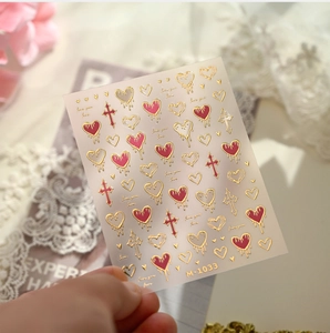Detail of gold-stamped heart and cross nail stickers M-1033 with romantic floral backdrop