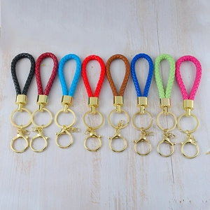Set of 8 colorful woven leather cord keychains with gold metal clasps on wood background