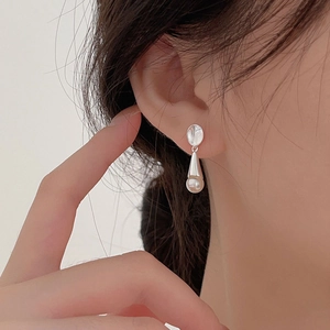 Close-up of minimalist 925 sterling silver pearl drop earrings on a model ear