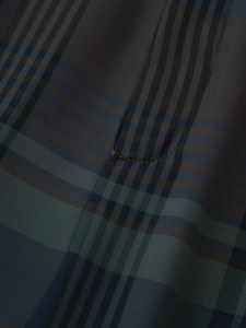 Vue macro détaillée montrant la texture du tissu écossais sombre et les coutures du pantalon