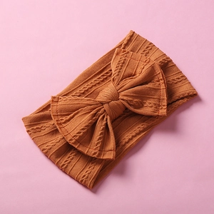 Detail of caramel nylon baby headband featuring cable knit patterns and a large bow