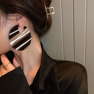 Close-up of oversized black and white striped acrylic hoop earrings on a model