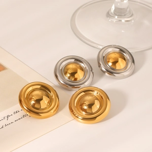 Macro detail of high-polished 18K gold and silver-toned round stud earrings on paper