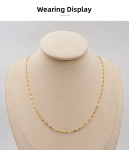 Detailed view of a delicate gold lip chain necklace on a beige jewelry display stand