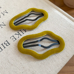 Detail view of mustard yellow flocked wavy hair clips on a textured beige book