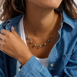 Primo piano della collana in acciaio al titanio dorato con perline turchesi