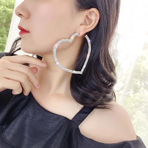 Boucles d'oreilles créoles cœur argentées avec strass brillants portées par un mannequin
