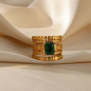Detailed close-up of a vintage gold layered ring with square emerald gem on beige silk