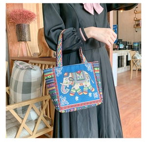 Close-up of ethnic embroidered handbag with colorful elephant pattern and woven handles