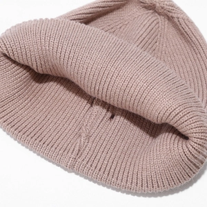 Close-up of pink knitted beanie featuring ribbed texture and warm elastic material details