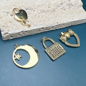 Close-up of golden heart lock, moon, and star pendants with shell and zircon details