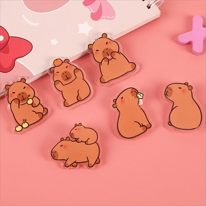 Cute brown capybara acrylic badges in six different poses on a pink background