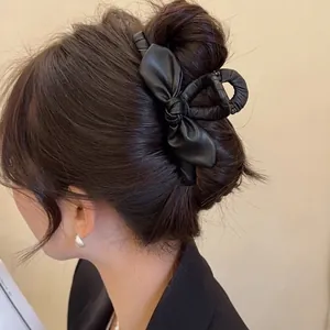 Elegante pinza per capelli in pelle nera con fiocco mostrata sui capelli di una modella