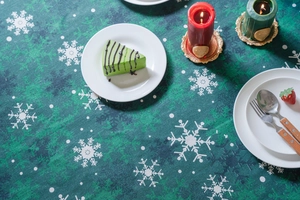 Détail de la nappe vert foncé avec imprimés de flocons de neige blancs et décor de fête