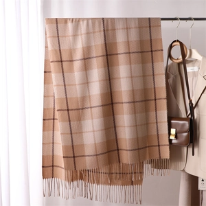 Classic brown and beige plaid cashmere-like scarf with fringe hanging on a hanger