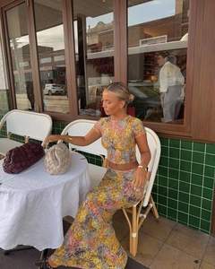 Detail showing high-waist floral maxi skirt and mesh crop top set in outdoor setting