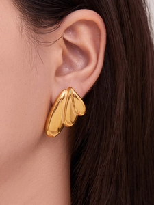 Close-up of triple-layered gold-plated angel wing earrings on female model