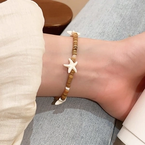 Detail of beach style anklet with brown beads and white starfish on ankle