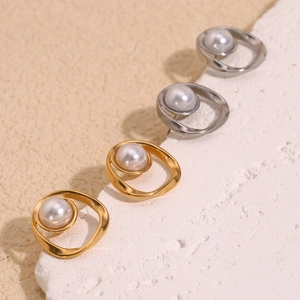 Detailed close-up of gold and silver irregular hollow earrings with round white pearls