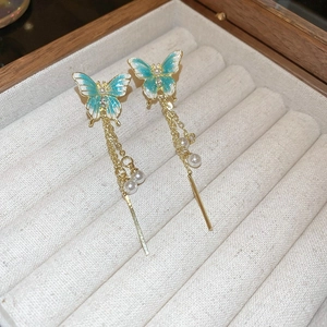 Détail de boucles d'oreilles papillon bleu avec glands perlés sur plateau velours