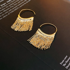 Detail of gold C-shaped earrings with metallic fringe tassels on a vintage book