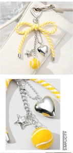 Detail of yellow and white striped ribbon keychain with silver heart and star charms