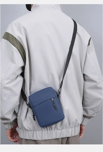 Blue nylon crossbody bag with adjustable strap shown on model in a casual setting