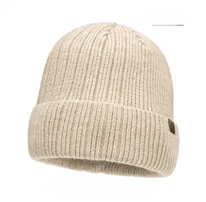 Close-up of beige knitted beanie featuring thick vertical ribs and a leather logo patch