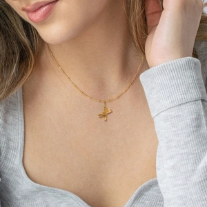 Gouden roestvrijstalen ketting met getextureerde letter X hanger gedragen door model
