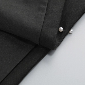 Gros plan du tissu tissé noir avec deux perles blanches décoratives sur le bord