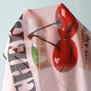 Detailed view of semi-transparent pink mesh fabric with red cherry and text print