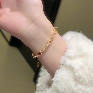 Close-up of 18k gold plated bracelet with amber resin stones and heart charm detail