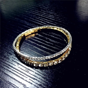 Macro detail of intertwined gold and silver rhinestone stretch bracelets on a wood surface