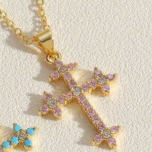 Macro shot of gold-plated cross pendant necklace with pink and white cubic zirconia