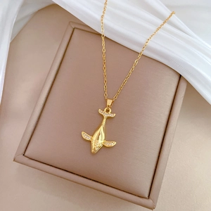 Detailed close-up of a gold whale pendant necklace with sparkling diamonds on silk