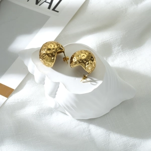 Detailed view of gold textured dome earrings on white shell display stand