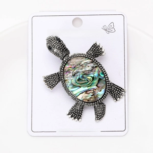Macro view of vintage turtle brooch with abalone shell inlay on display card