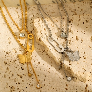 Detail of gold and silver layered butterfly necklaces with paperclip and zircon pendants