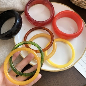 Close-up of assorted resin rings in various colors and thickness on white ceramic plate