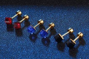 Detail of square-cut gem earrings in red, blue, and black with gold claw settings