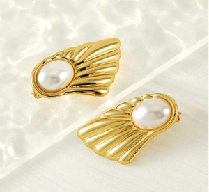 Detail of gold fan-shaped stud earrings with vintage texture and large oval pearls