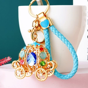 Detail of golden pumpkin carriage keychain with colorful rhinestones and blue woven strap