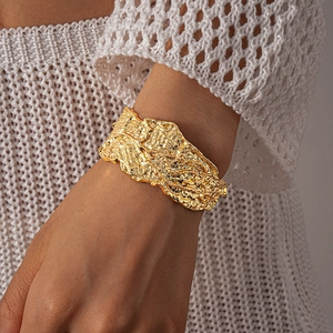 Detailed view of wide gold cuff bracelet featuring irregular molten lava metal texture