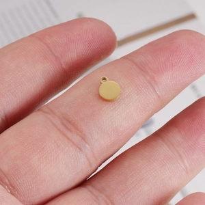 Golden mirror stainless steel 5.5x7mm round pendant charm held by fingers for DIY jewelry