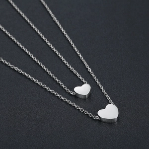 Detailed view of silver double-layered heart pendant necklaces on dark matte surface