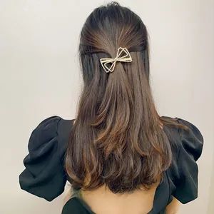 Detail view of double-layered hollow bow hair clip with white pearls on model hair