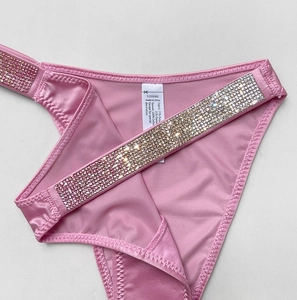 Detailed macro view of pink satin fabric and sparkling rhinestone side straps on thong