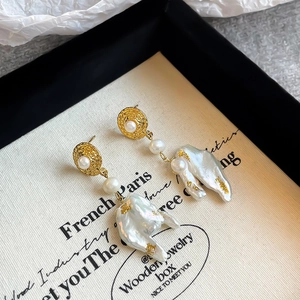 Macro detail of Baroque pearl drop earrings with textured gold finish and French style