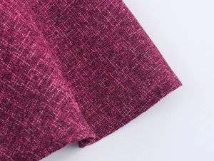 Macro detail of dark magenta tweed fabric showing intricate woven texture and fibers