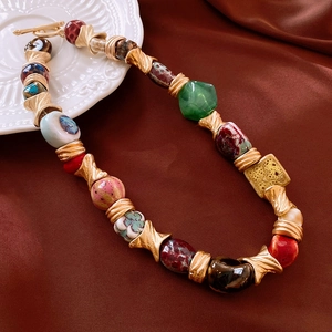Flat lay of vintage colorful ceramic flower beaded necklace on deep red satin cloth